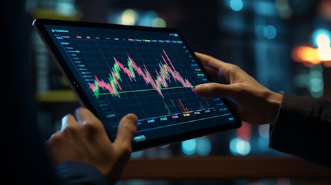 A close-up of a hand holding a tablet with financial charts and graphs.