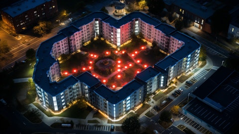 An aerial view of a multi-family residential complex with the company's logo illuminated in the front.