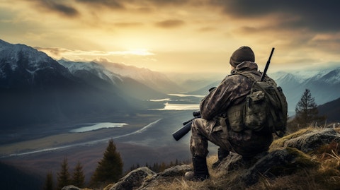 A close-up of a hunter holding a rifle with the scenic landscape in the background.