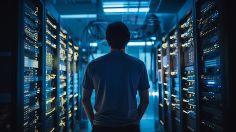 A technician in a server room of a corporate office surrounded by servers and networking equipment.