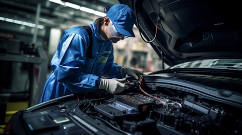 A technician wearing a safety suit and goggles working on a battery pack for an electric vehicle.