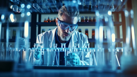 A research scientist in a lab wearing safety glasses, surrounded by laboratory equipment testing life science samples.