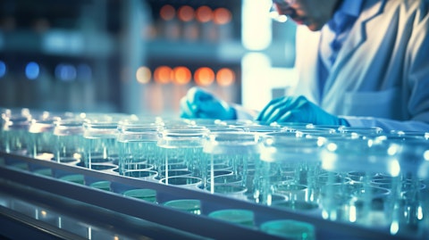 A close up of a scientist in a lab coat examining a beaker of cell cultures.