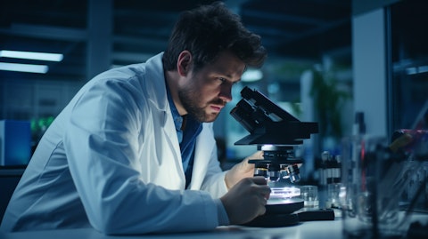 A scientist in a lab coat working with a microscope in a research laboratory.