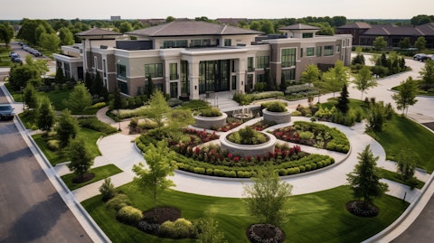 An aerial shot of a modern health care property, its front entrance flanked by well-manicured gardens.