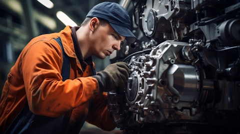 A worker in a factory suit inspecting the components of a diesel engine.
