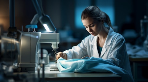 A woman working on a sewing machine, producing a lab coat.