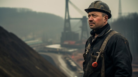 A coal miner at their place of work, with the coal reserves in the backdrop.