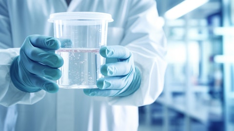 Closeup of a biopharmaceutical worker holding a beaker of white liquid in a laboratory.