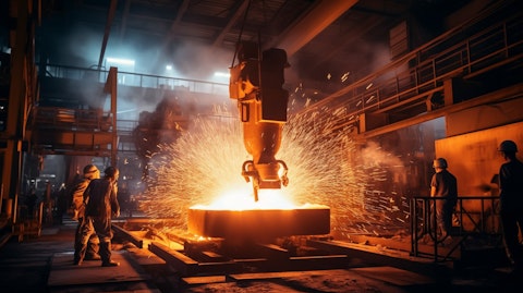 A large steel ingot being forged with sparks flying from a steel mill.
