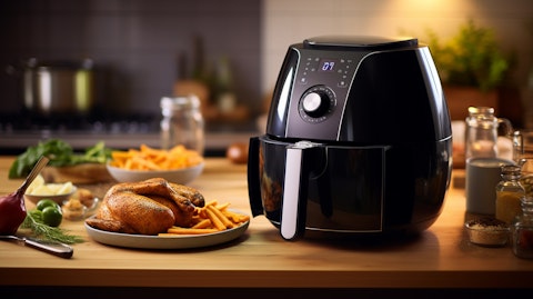 A customer holding a hot air fryer in their kitchen, the convection current visible.
