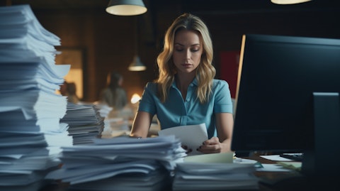 A loan officer typing away in her office with stacks of paperwork in the background.