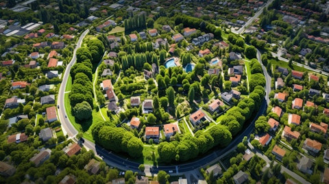An aerial view of a residential neighborhood with green trees and a park in the foreground.