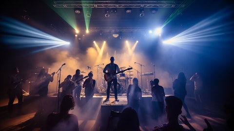 A group of musicians performing on stage with the audience in the background.