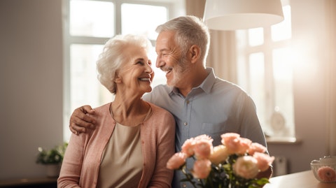 A senior couple smiling and embracing in a bright, spacious independent living apartment.