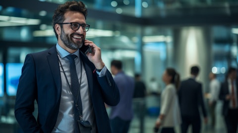 A communication professional speaking on the phone with a smiling customer in the background.