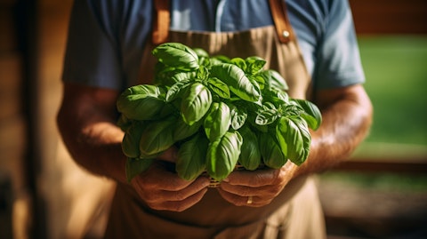 A farmer holding a freshly-harvested bundle of basil, symbolizing the company's commitment to growing crops.