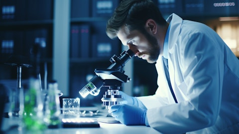 A researcher in a lab coat studying a clinical sample under a microscope.