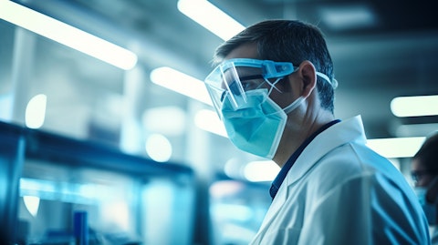 A medical scientist in a lab wearing a face mask and safety glasses, researching biomarkers.