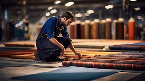 A worker inspecting a newly manufactured rug on the factory floor.