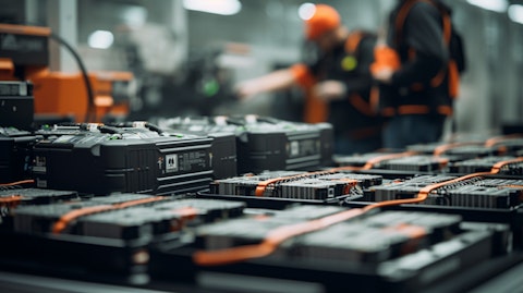 An assembly line of lithium-ion batteries for energy storage solutions with workers in the background.
