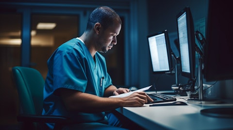 A medical professional in scrubs typing on an electronic medical record, depicting the value of the company's medical services.