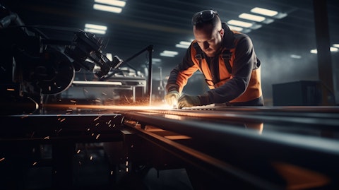 A manufacturing space with a worker in the foreground, illuminated by a cutting tool on the leather belt strip.