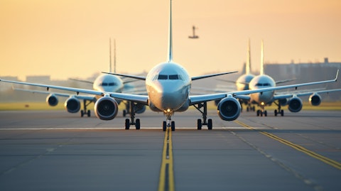 A row of commercial airplanes on a runway, their engines running and ready for takeoff.