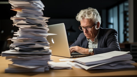 A senior analyst pouring over a stack of data analysis reports on their laptop.