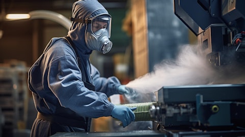 A factory worker wearing protective gear and operating a machine used in lead recycling.