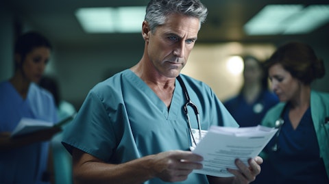 A medical professional in scrubs discussing a patient's records with a multidisciplinary team.