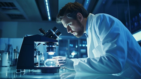 A scientist in a labcoat inspecting a microscope focusing on a microorganism related to the biopharmaceutical company's therapies.