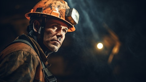 A miner in a safety helmet working in an underground tunnel.