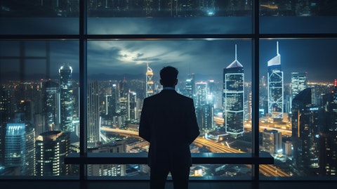 An executive looking out a skyscraper window overlooking a city skyline of connected lights.