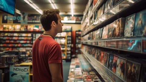 An employee at an entertainment retail storefront stocking new and pre-owned movies.