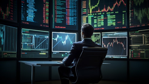 An executive in a suit on the floor of a trading exchange, with screens of stock prices in the background.